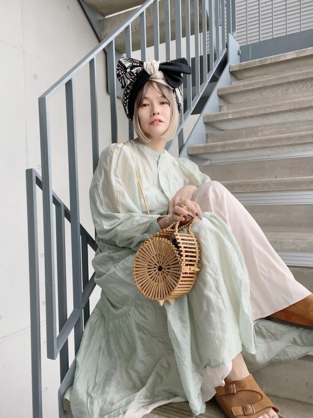 ベージュ系のかごバッグ、グリーン系のワンピース、ホワイト系のワンピースを着用したレディースの春コーディネートの4枚目の写真