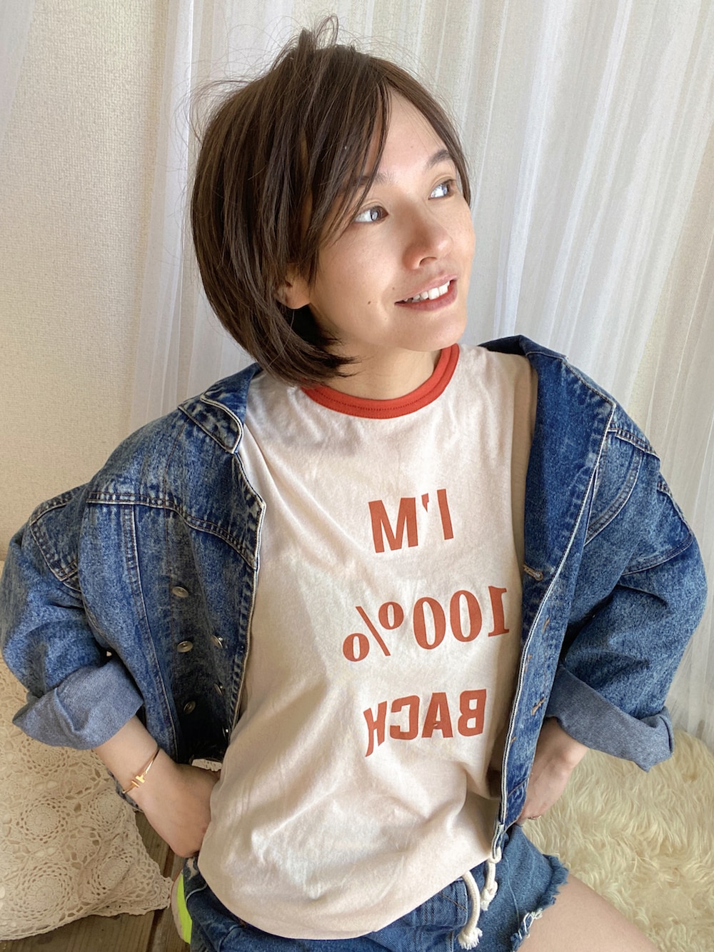 ブルー系のデニムパンツ、ブルー系のデニムジャケット、オレンジ系のTシャツ/カットソーを着用したレディースの冬コーディネートの4枚目の写真