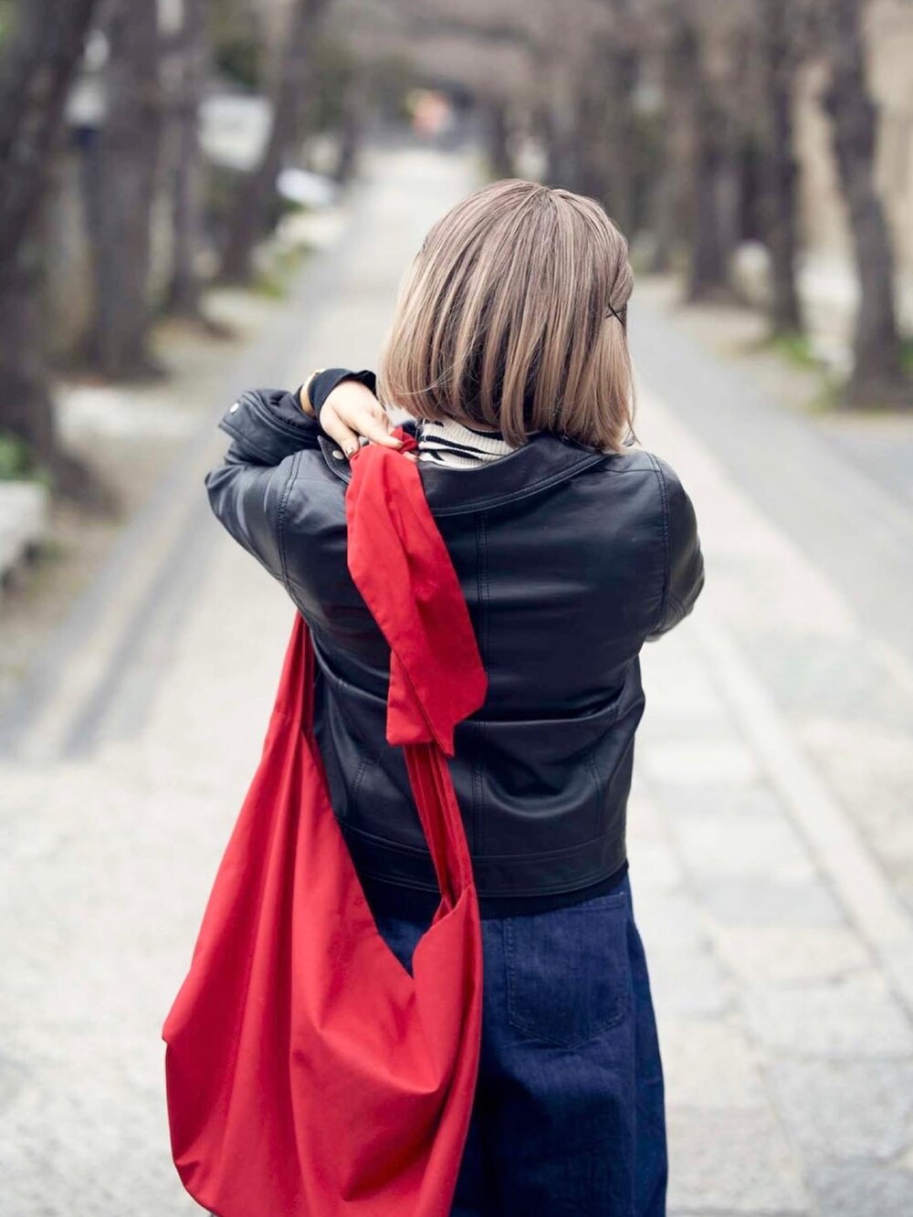 ブルー系のデニムパンツ、ホワイト系のニット/セーター、レッド系のショルダーバッグを着用したレディースの春コーディネートの3枚目の写真