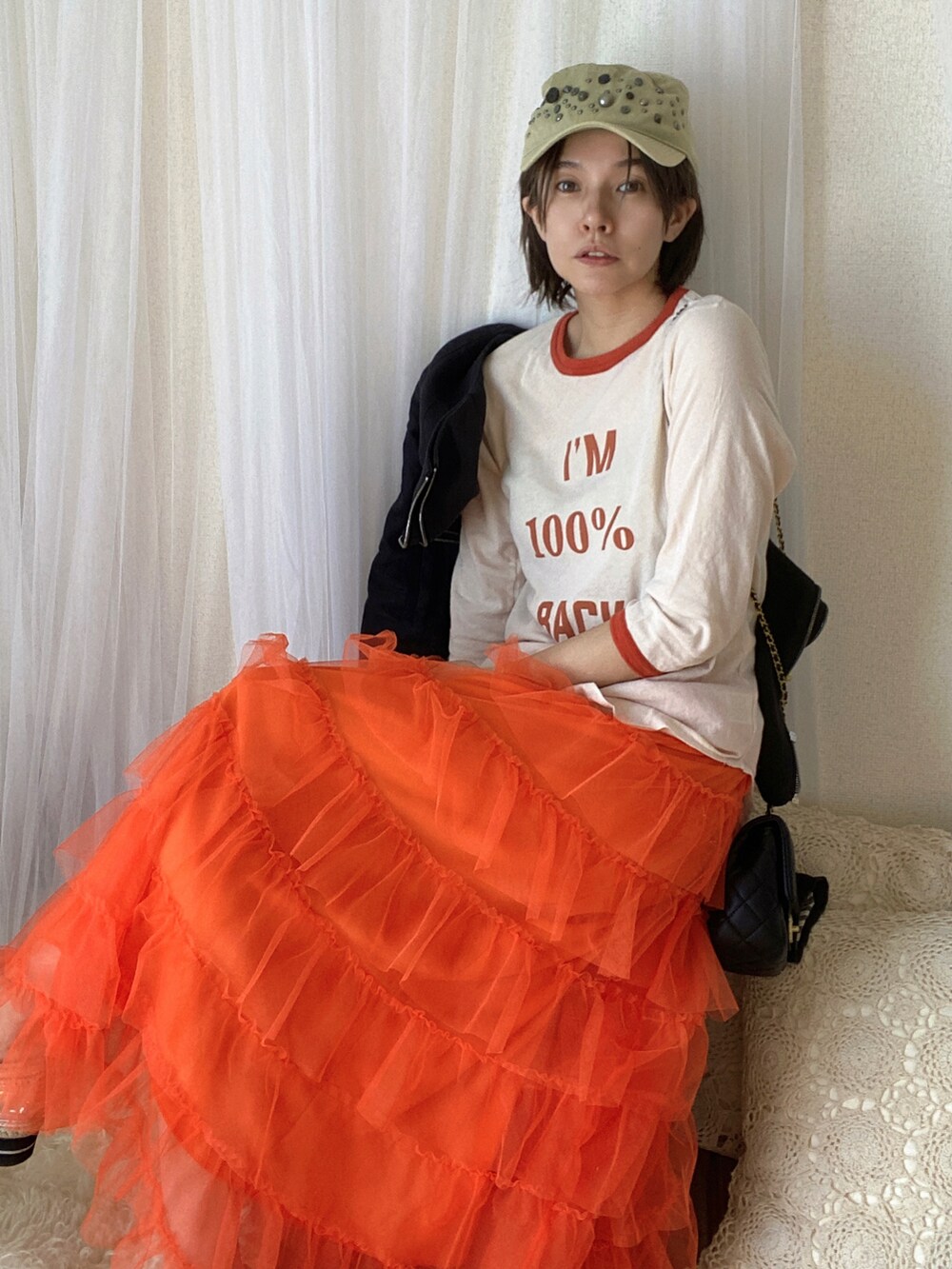 オレンジ系のTシャツ/カットソー、オレンジ系のスカート、シルバー系のシューズを着用したレディースの冬コーディネートの2枚目の写真