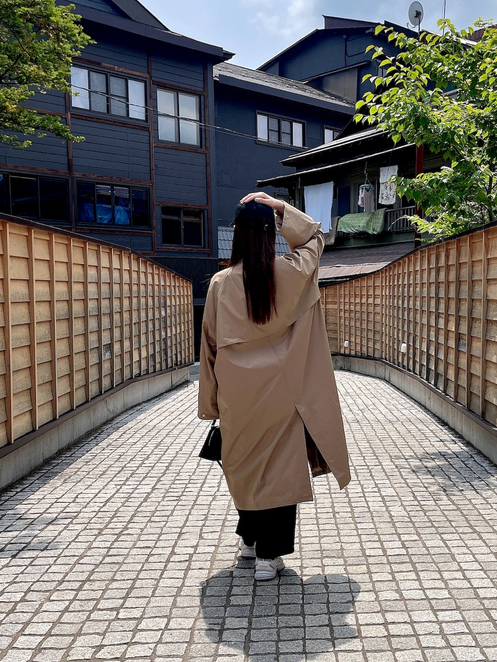 ベージュ系のステンカラーコートを着用したレディースの夏コーディネートの2枚目の写真