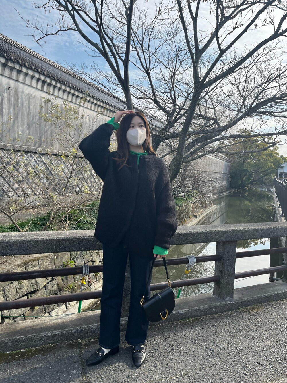 ブラック系のショルダーバッグ、ブラック系のその他アウター、ブルー系のデニムパンツを着用したレディースの春コーディネートの2枚目の写真