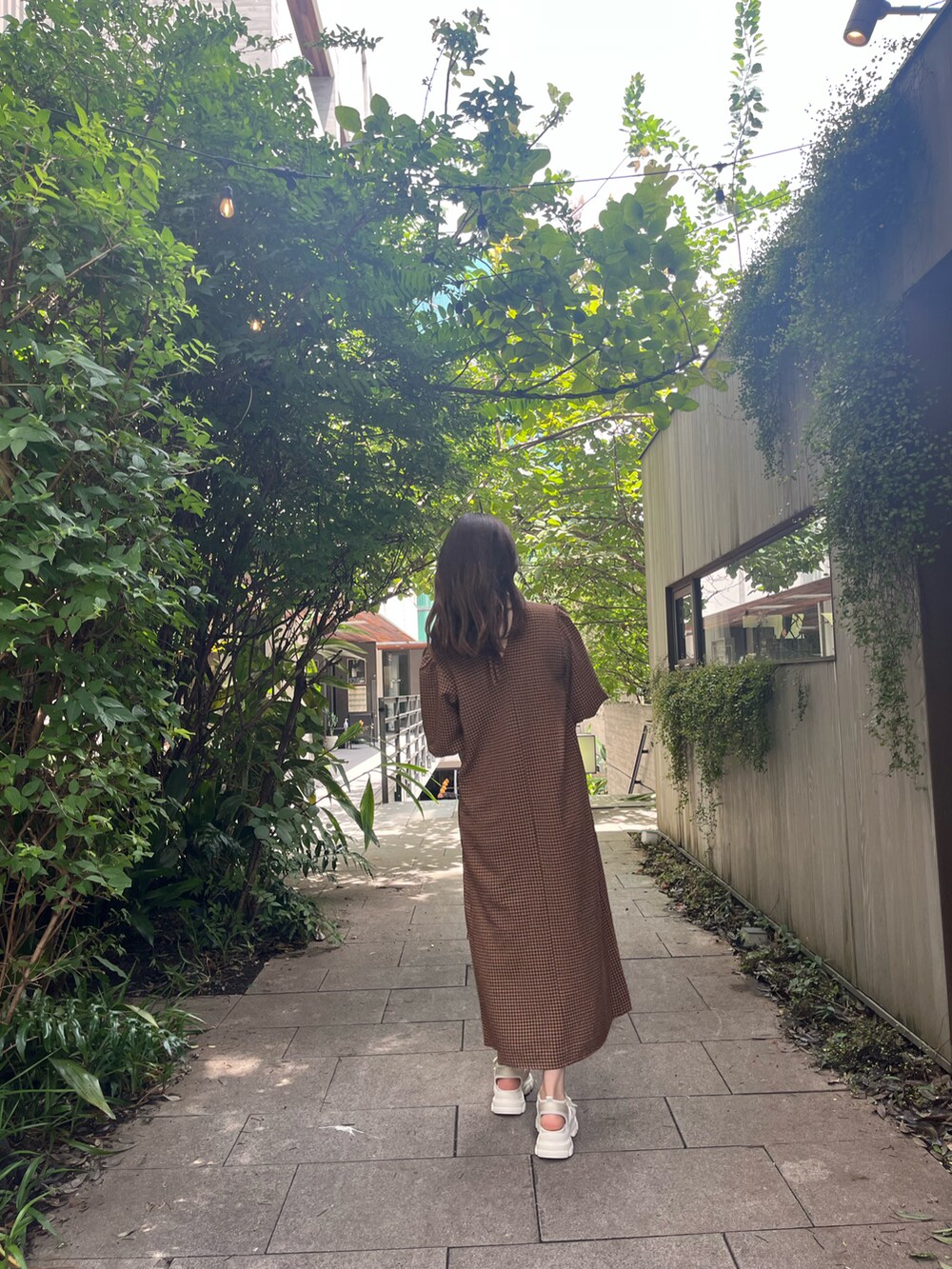 ブラック系のハンドバッグ、オレンジ系のワンピース、ベージュ系のサンダルを着用したレディースの夏コーディネートの2枚目の写真