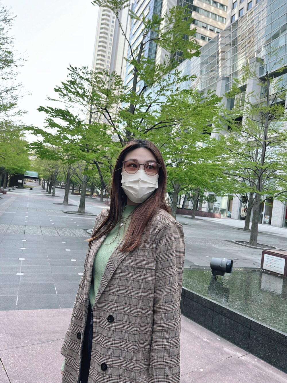 グリーン系のニット/セーター、ブルー系のデニムパンツ、ベージュ系のサングラスを着用したレディースの春コーディネートの3枚目の写真