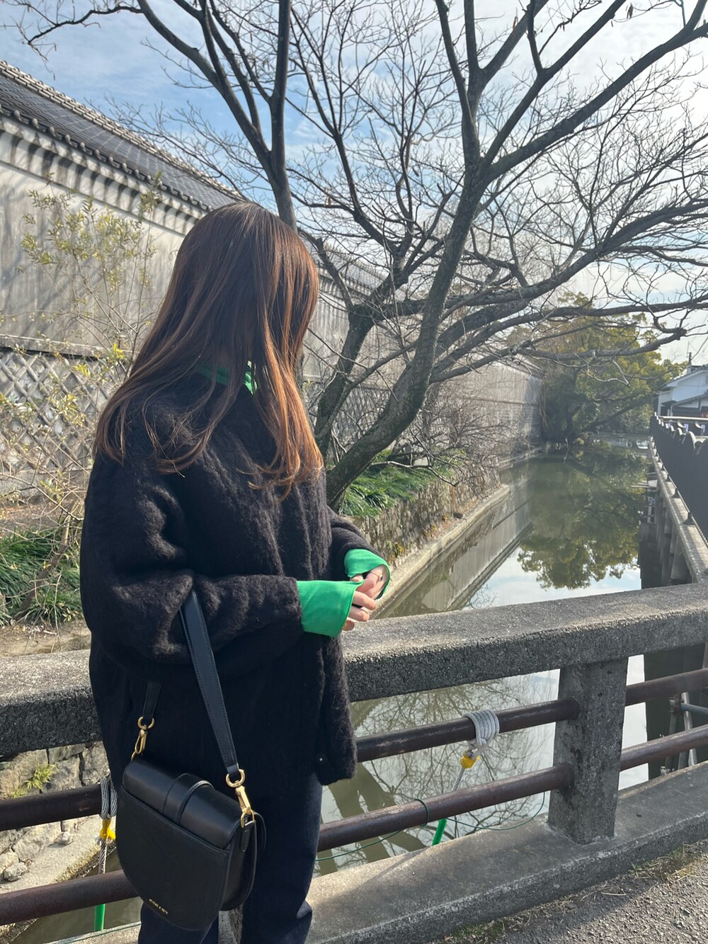 ブラック系のショルダーバッグ、ブラック系のその他アウター、ブルー系のデニムパンツを着用したレディースの春コーディネートの3枚目の写真