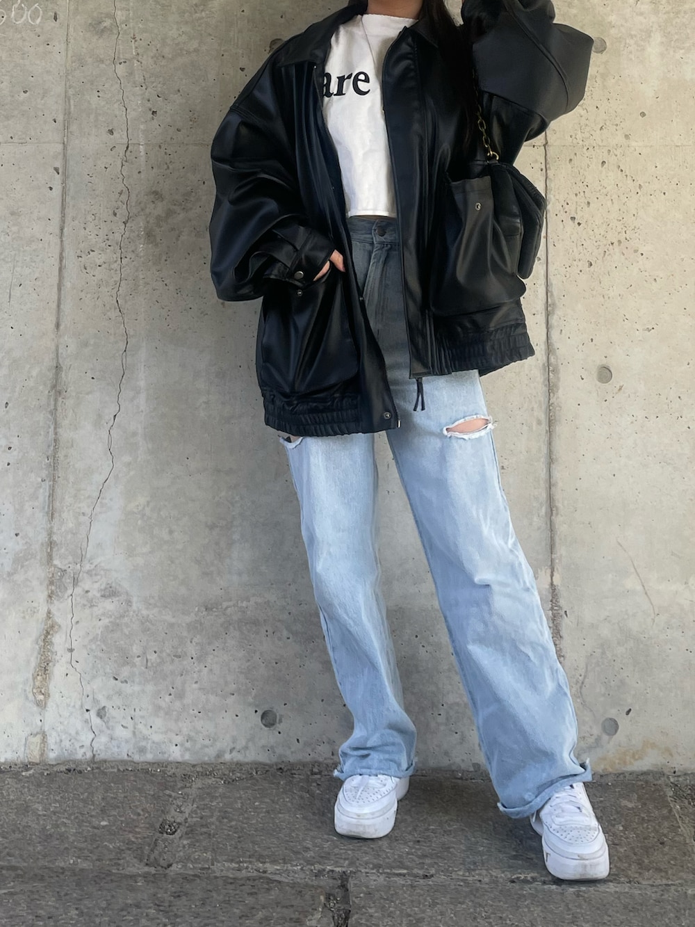 ホワイト系のTシャツ/カットソー、ブラック系のライダースジャケット、ブルー系のデニムパンツを着用したレディースの冬コーディネートの3枚目の写真