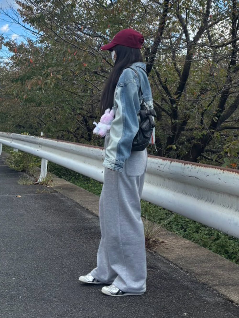 シルバー系のスニーカー、ブラック系のショルダーバッグ、ブルー系のデニムジャケットを着用したレディースの秋コーディネートの2枚目の写真