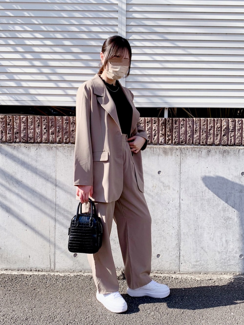 グレー系のテーラードジャケット、ブラック系のショルダーバッグ、ホワイト系のスニーカーを着用したレディースの春コーディネートの3枚目の写真