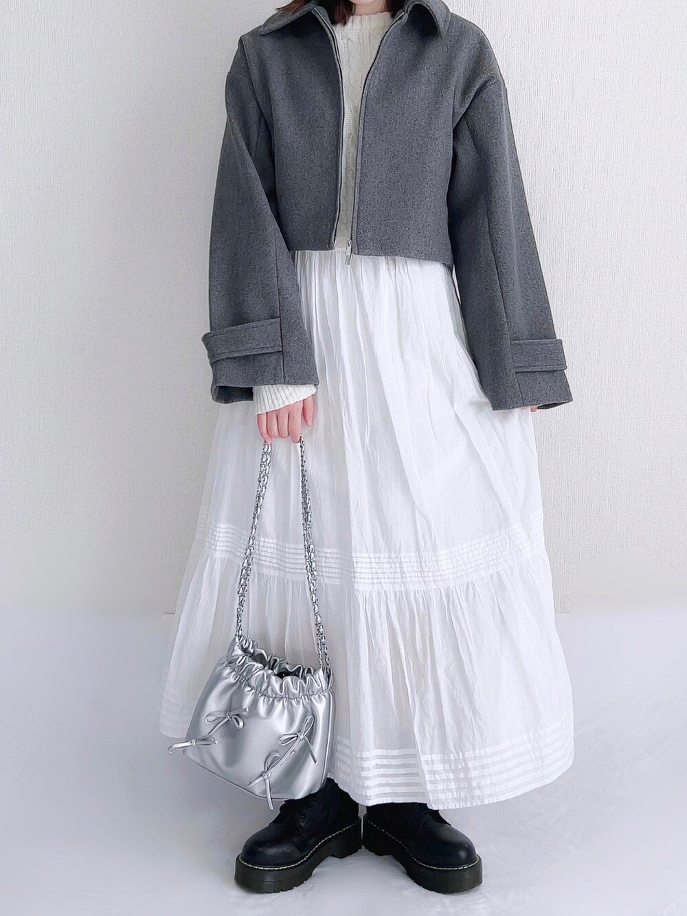 グレー系のブルゾン、ホワイト系のニット/セーター、ホワイト系のスカートを着用したレディースの秋コーディネートの2枚目の写真