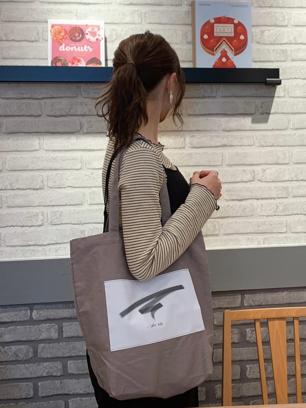 グレー系のトートバッグ、ベージュ系のトップス、ブラック系のサロペット/オーバーオールを着用したレディースの春コーディネートの3枚目の写真