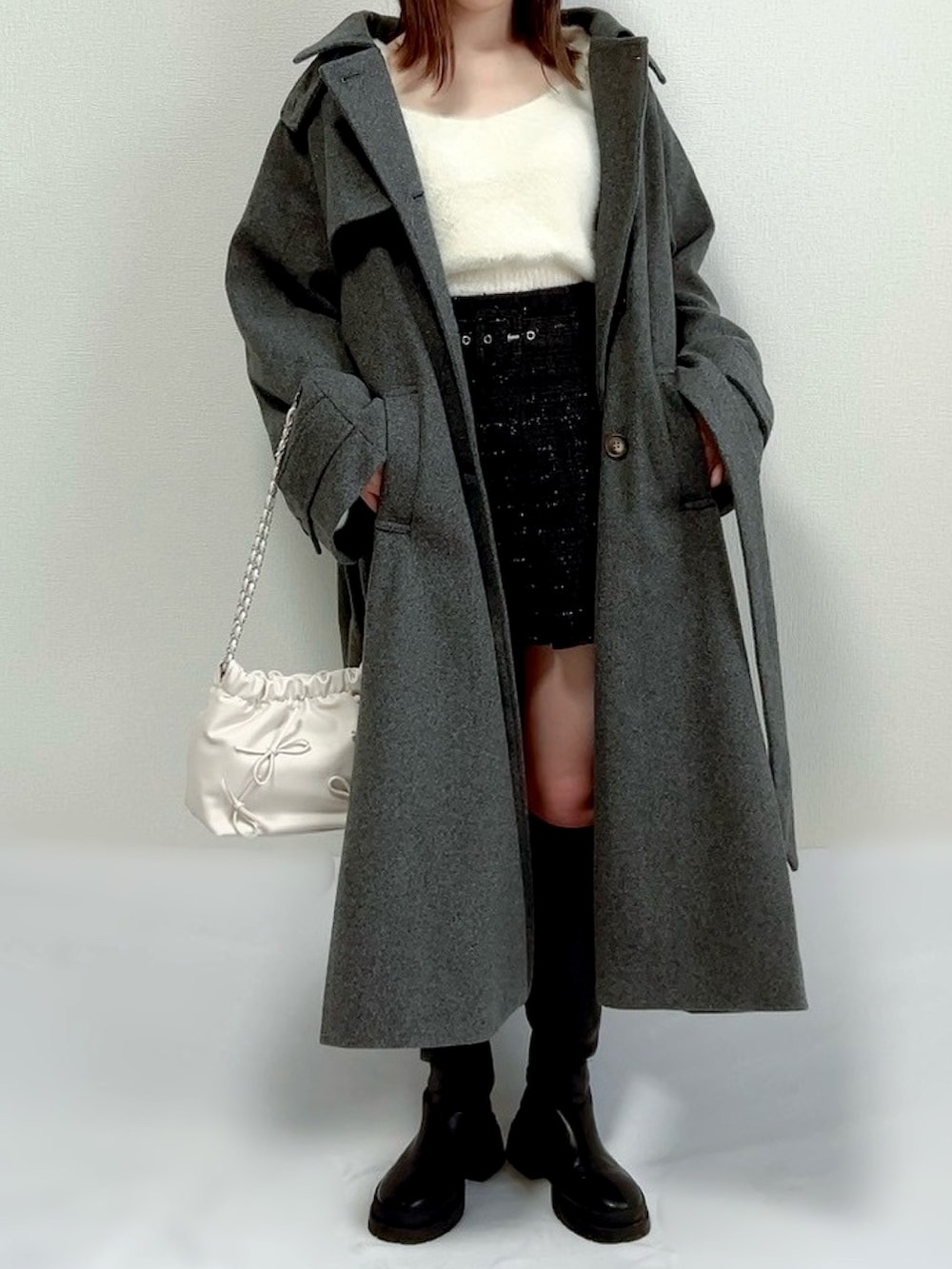 グレー系のチェスターコート、ブルー系のニット/セーター、ブラック系のスカートを着用したレディースの冬コーディネートの2枚目の写真