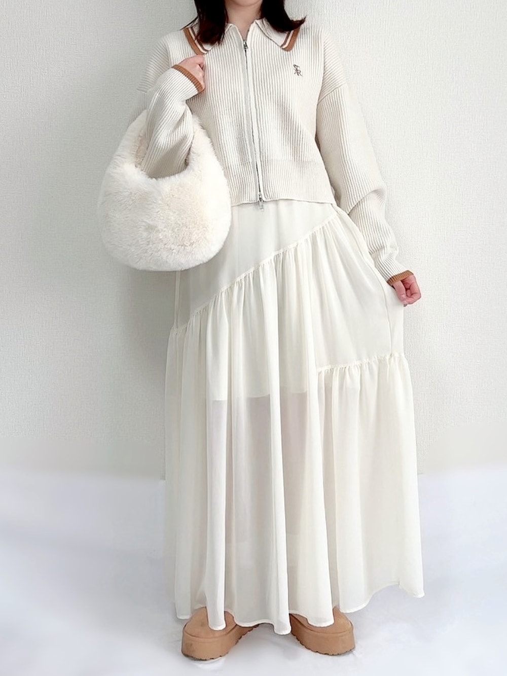 ホワイト系のニット/セーター、ホワイト系のスカート、ホワイト系のバッグを着用したレディースの冬コーディネートの2枚目の写真