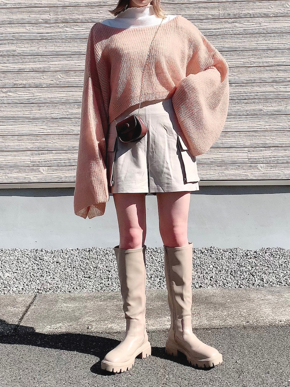 ピンク系のトップス、ベージュ系のパンツ、ブラウン系のショルダーバッグを着用したレディースの冬コーディネートの3枚目の写真