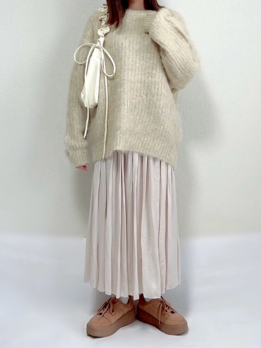 ベージュ系のニット/セーター、ベージュ系のスカート、ホワイト系のバッグを着用したレディースの冬コーディネートの2枚目の写真