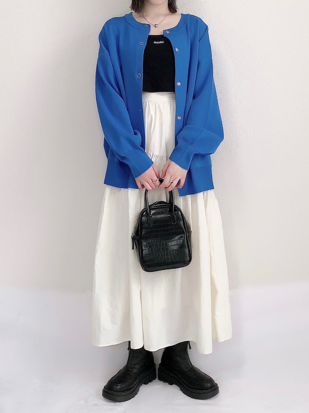 ブルー系のカーディガン/ボレロ、ブラック系のキャミソール、ホワイト系のスカートを着用したレディースの春コーディネートの2枚目の写真