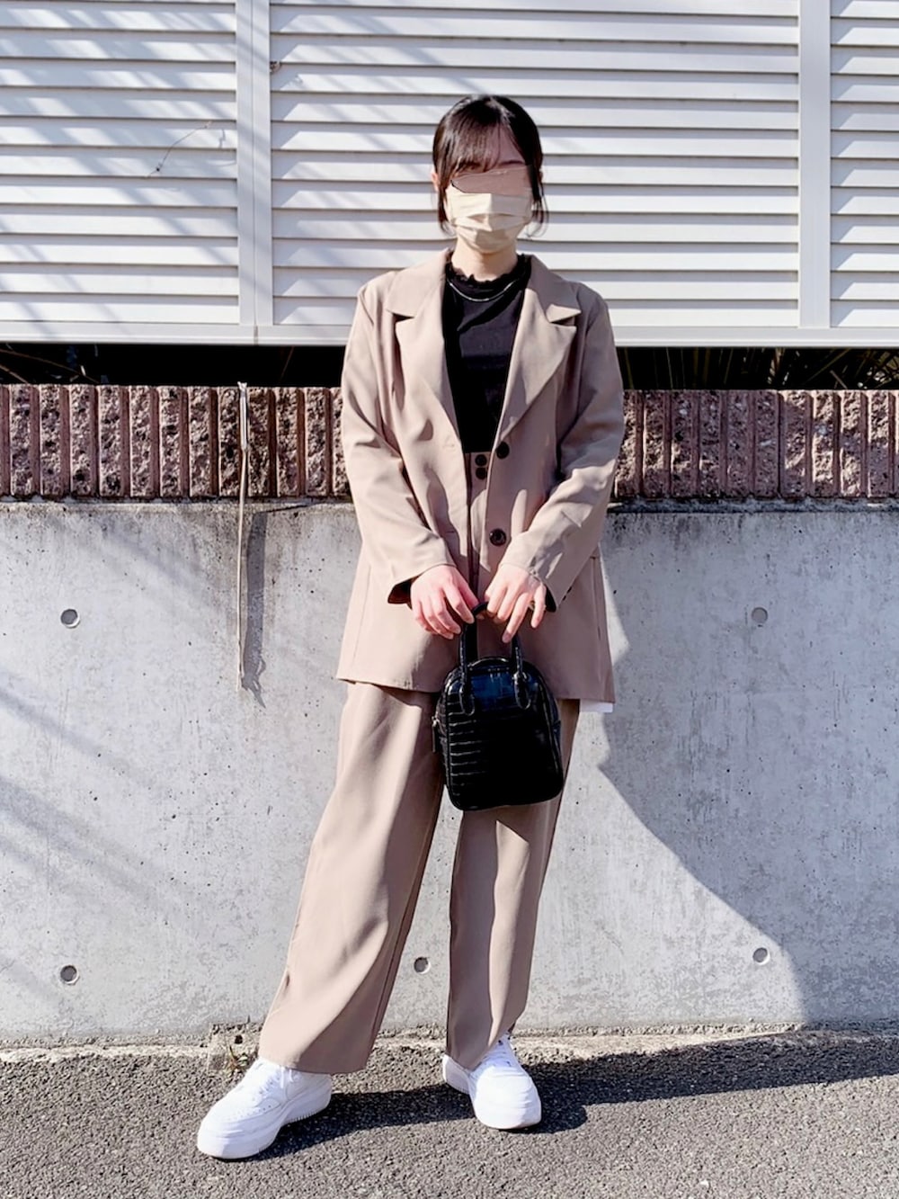 グレー系のテーラードジャケット、ブラック系のショルダーバッグ、ホワイト系のスニーカーを着用したレディースの春コーディネートの2枚目の写真