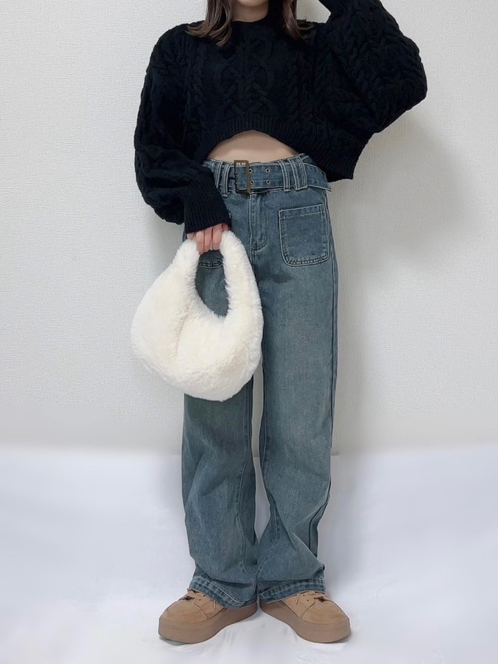 ブラック系のワンピース、ブルー系のデニムパンツ、ホワイト系のバッグを着用したレディースの冬コーディネートの2枚目の写真