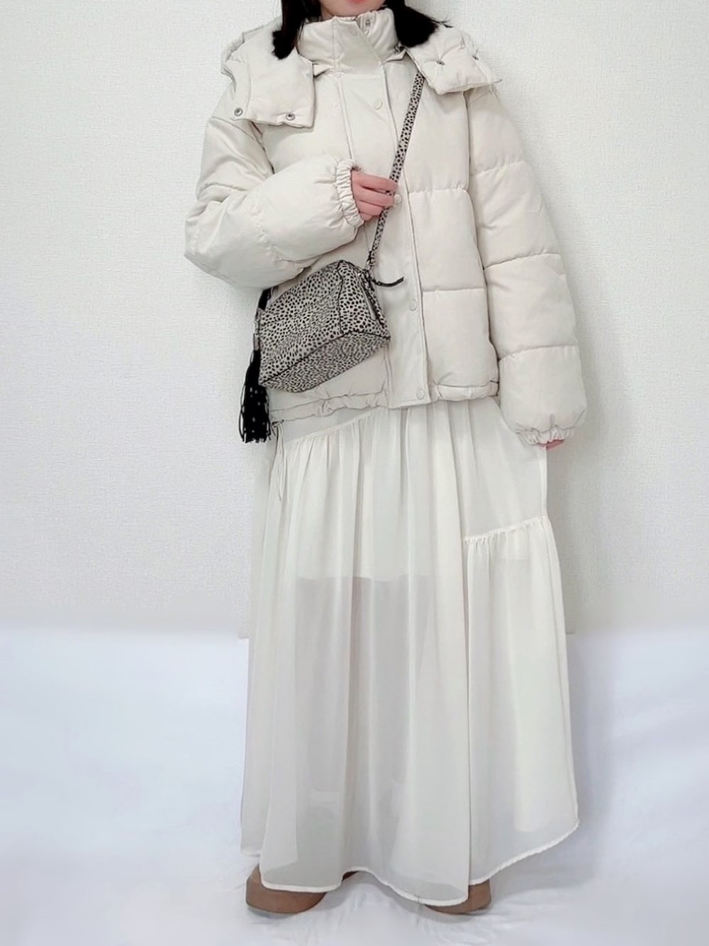 ホワイト系のダウンジャケット/コート、ブラウン系のニット/セーター、ホワイト系のスカートを着用したレディースの冬コーディネートの2枚目の写真