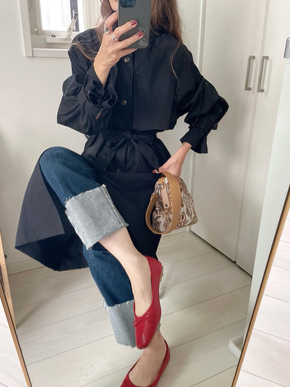 ブラック系のトレンチコートを着用したレディースの秋コーディネートの2枚目の写真