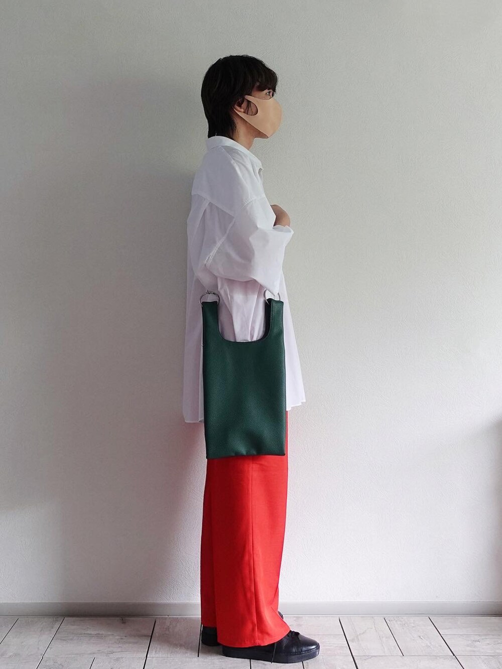 グリーン系のショルダーバッグ、レッド系のスラックス、ブラック系のスニーカーを着用したメンズの春コーディネートの2枚目の写真