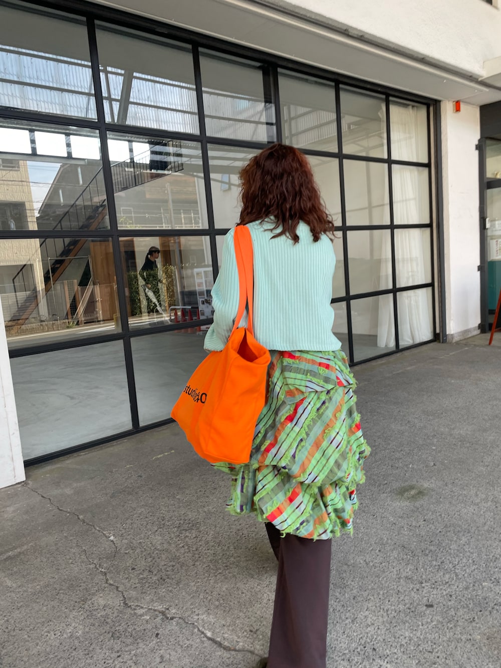 オレンジ系のトートバッグ、グリーン系のスカート、ブラウン系のその他パンツを着用したレディースの秋コーディネートの3枚目の写真