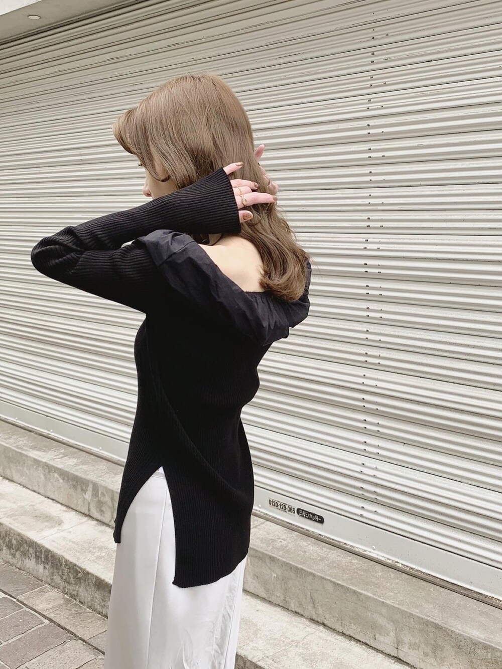 ブラック系のニット/セーター、グレー系のスカート、ブラック系のサンダルを着用したレディースの春コーディネートの4枚目の写真