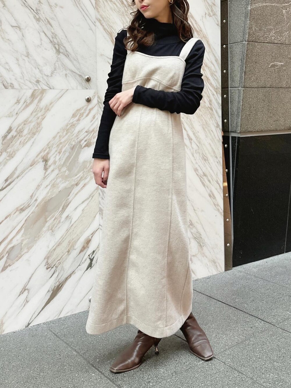 ベージュ系のジャンパースカート、ブラック系のTシャツ/カットソーを着用したレディースの冬コーディネートの2枚目の写真