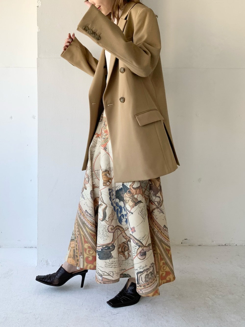 ベージュ系のテーラードジャケット、ホワイト系のニット/セーター、イエロー系のスカートを着用したレディースの春コーディネートの2枚目の写真