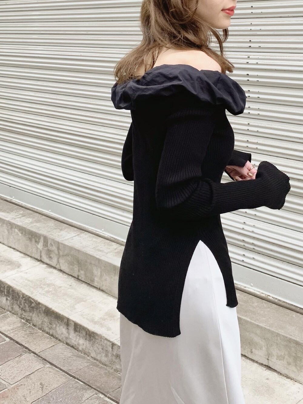 ブラック系のニット/セーター、グレー系のスカート、ブラック系のサンダルを着用したレディースの春コーディネートの3枚目の写真