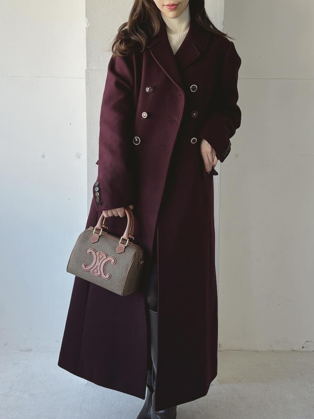 レッド系のチェスターコート、ブラウン系のブーツ、ホワイト系のニット/セーターを着用したレディースの冬コーディネートの3枚目の写真