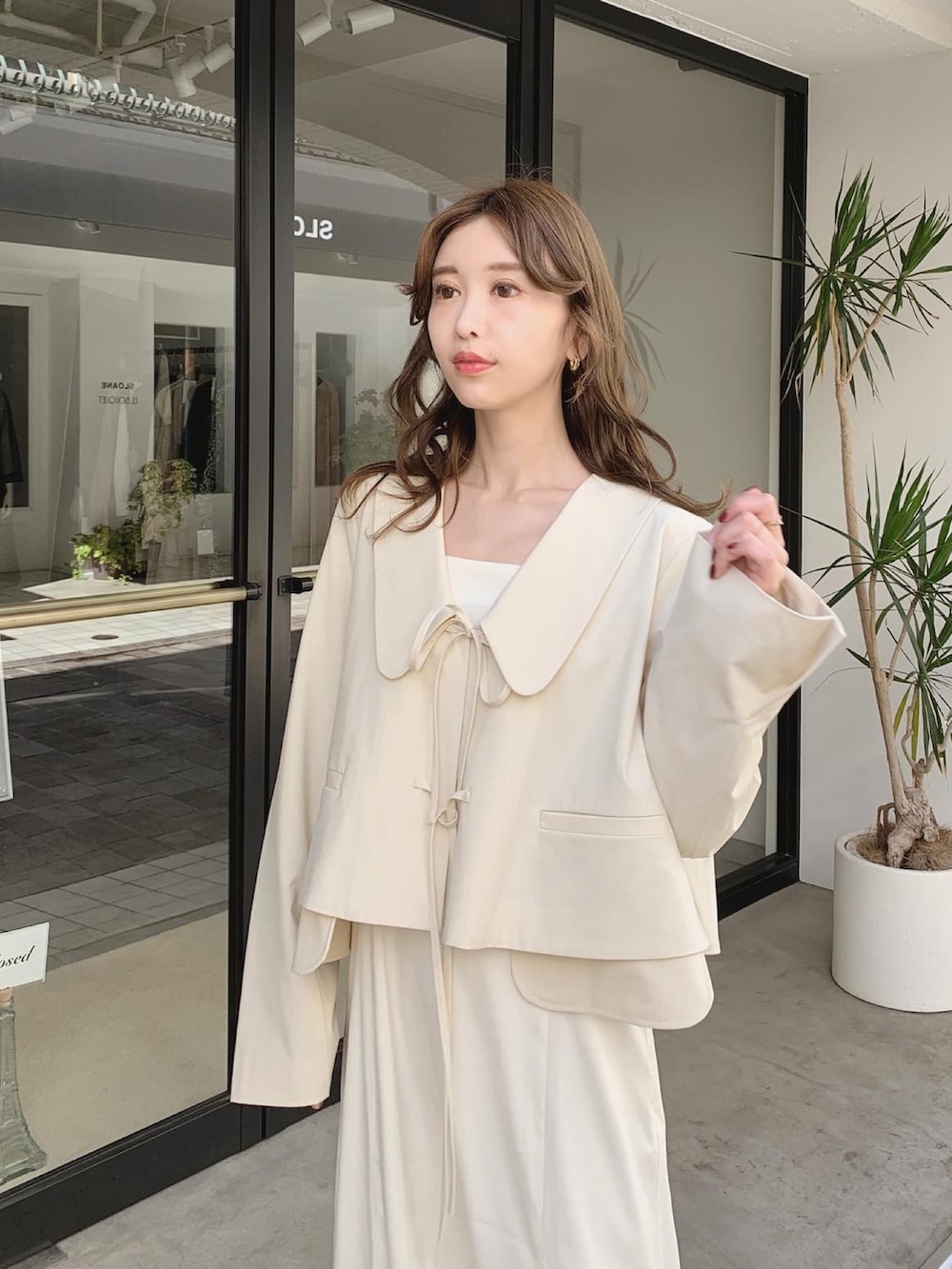 ホワイト系のテーラードジャケット、ホワイト系のワンピース、ブラウン系のブーツを着用したレディースの秋コーディネートの3枚目の写真