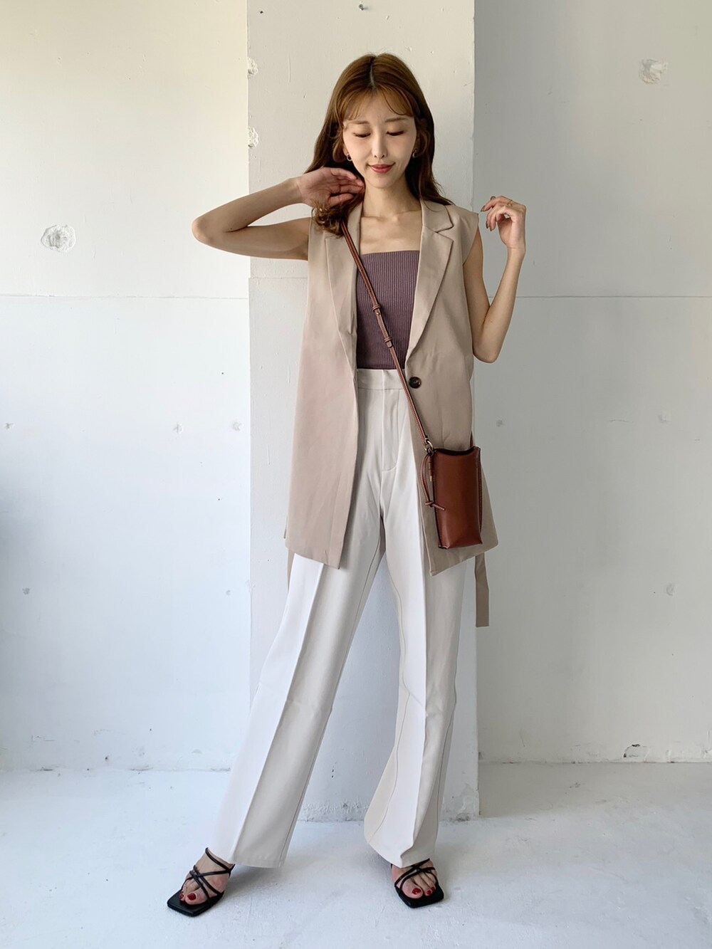 ベージュ系のベスト、ホワイト系のその他パンツ、ブラック系のサンダルを着用したレディースの夏コーディネートの2枚目の写真