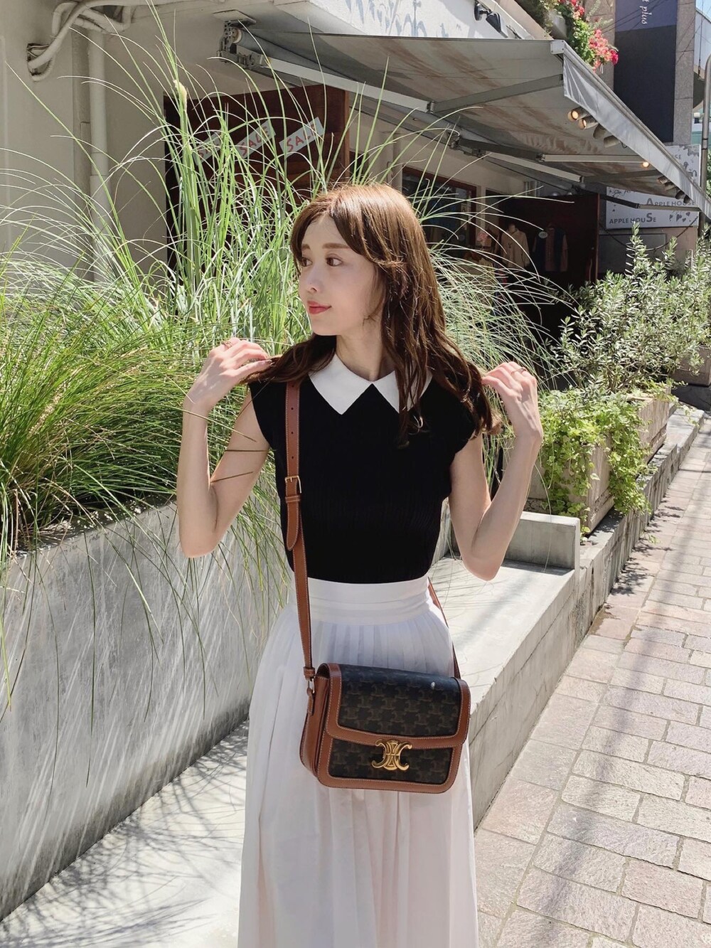 ブラック系のその他トップス、ホワイト系のスカート、ブラウン系のバッグを着用したレディースの夏コーディネートの2枚目の写真