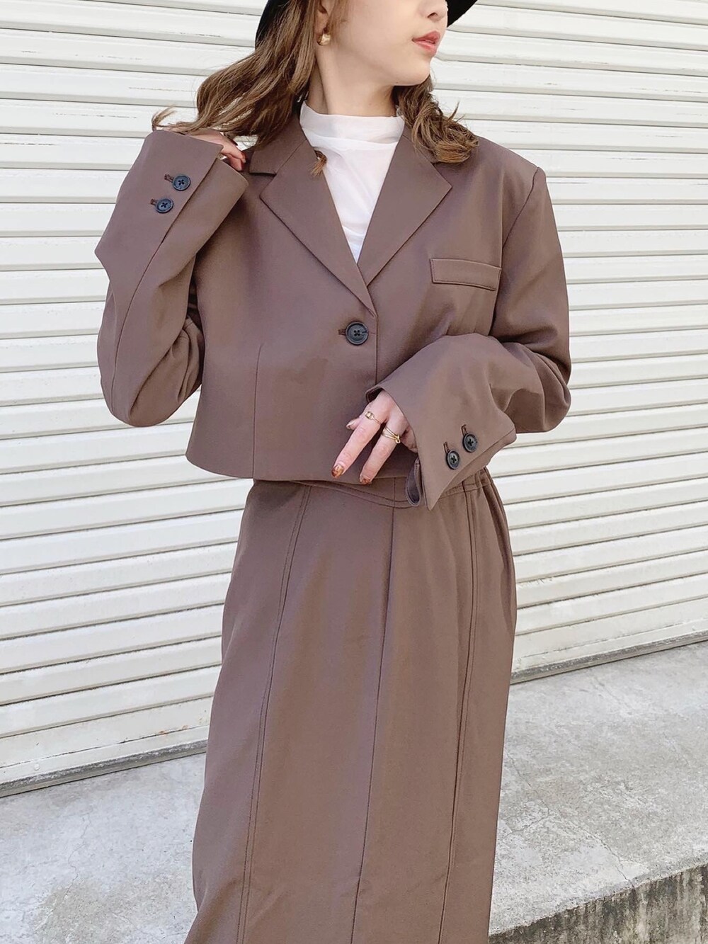 ブラウン系のテーラードジャケット、ブラウン系のスカート、ホワイト系のTシャツ/カットソーを着用したレディースの秋コーディネートの4枚目の写真