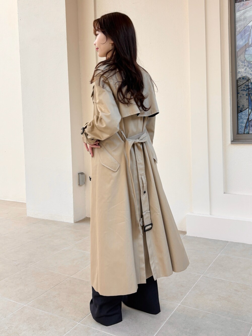 ベージュ系のトレンチコート、ベージュ系のバッグ、ブルー系のその他パンツを着用したレディースの冬コーディネートの4枚目の写真