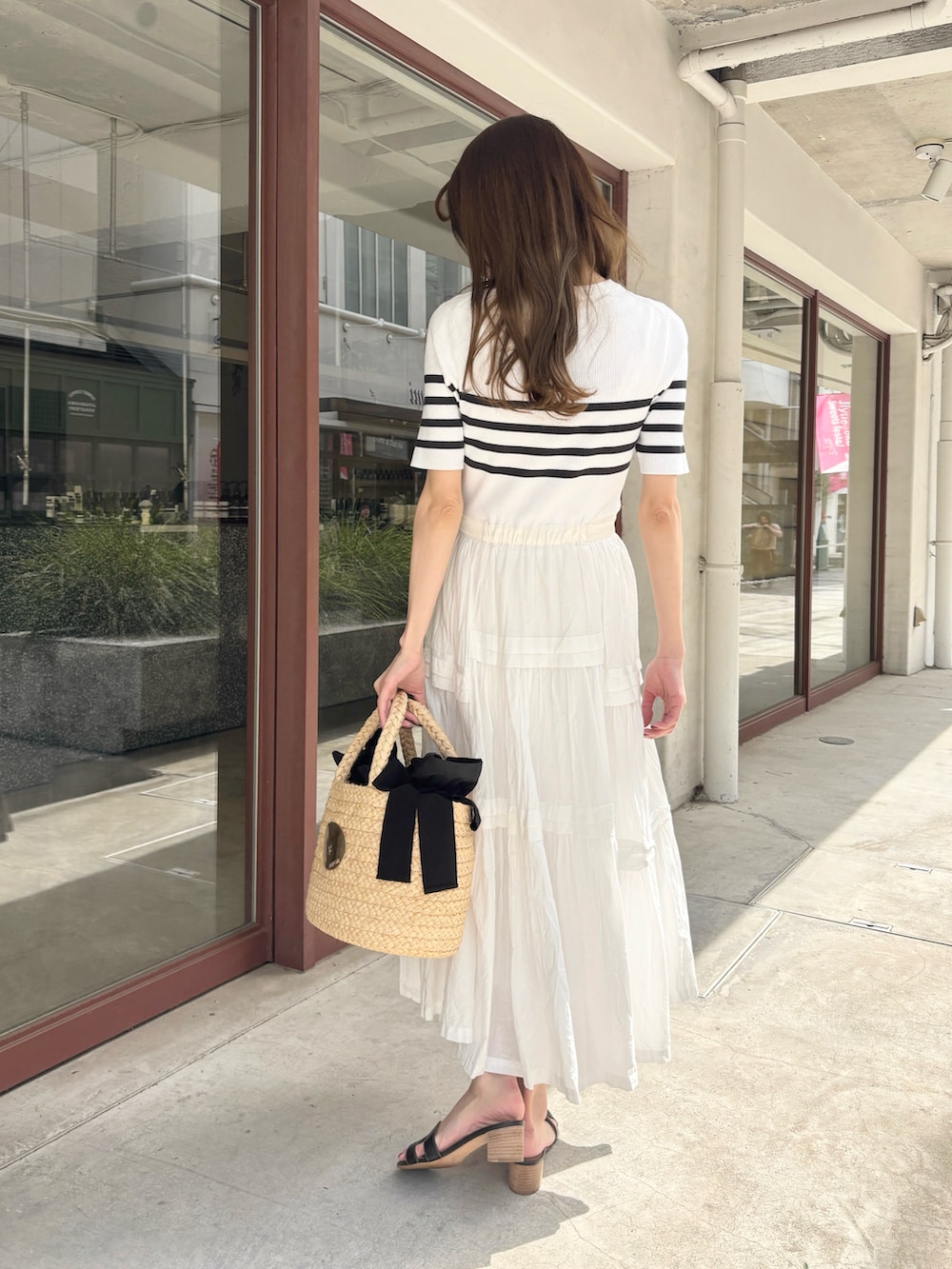 ホワイト系のワンピース、ブラック系のサンダル、ベージュ系のかごバッグを着用したレディースの夏コーディネートの3枚目の写真