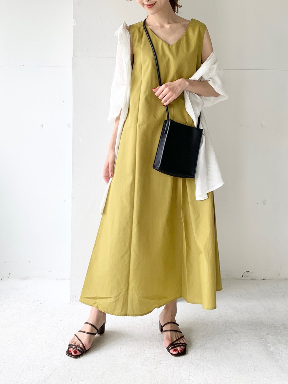 イエロー系のワンピース、ホワイト系のシャツ/ブラウス、ブラウン系のサンダルを着用したレディースの夏コーディネートの3枚目の写真