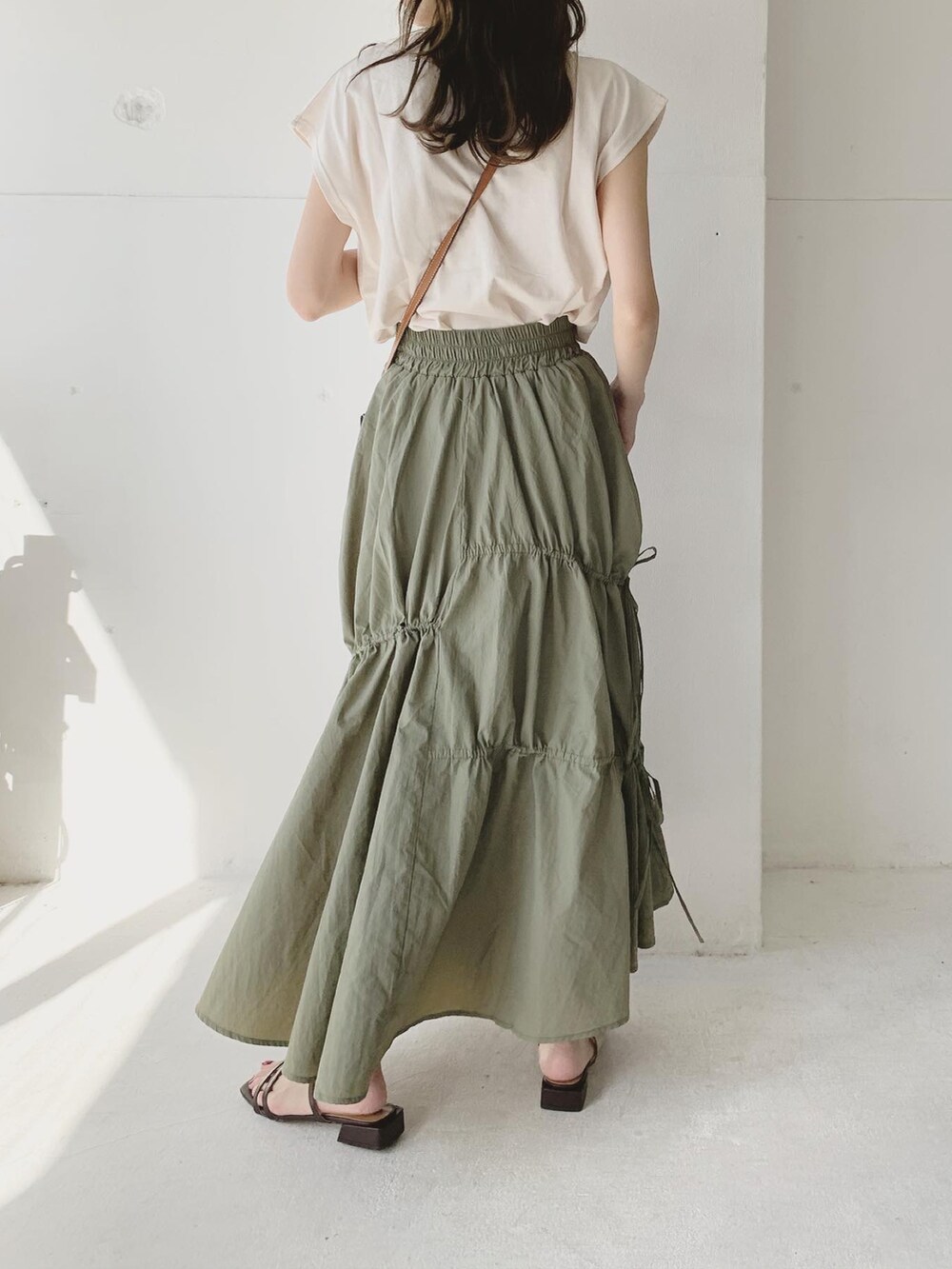 グリーン系のスカート、ブラウン系のサンダル、ホワイト系のTシャツ/カットソーを着用したレディースの夏コーディネートの3枚目の写真