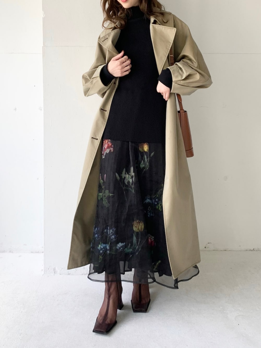 ベージュ系のトレンチコート、ブラック系のスカート、ブラック系のTシャツ/カットソーを着用したレディースの春コーディネートの3枚目の写真