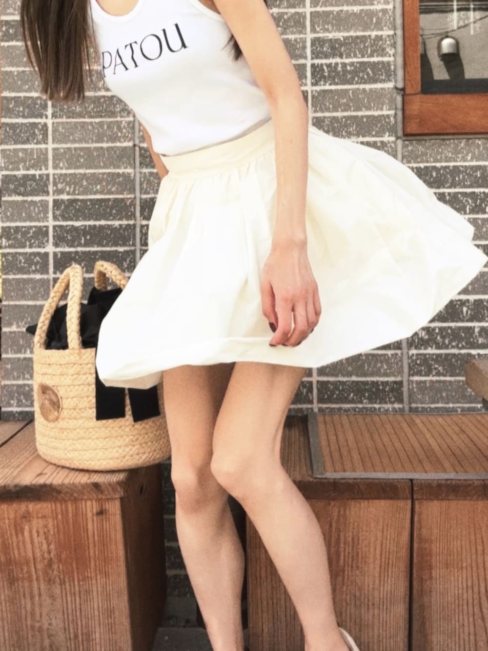 ホワイト系のトップス、ホワイト系のスカート、ベージュ系のかごバッグを着用したレディースの秋コーディネートの2枚目の写真