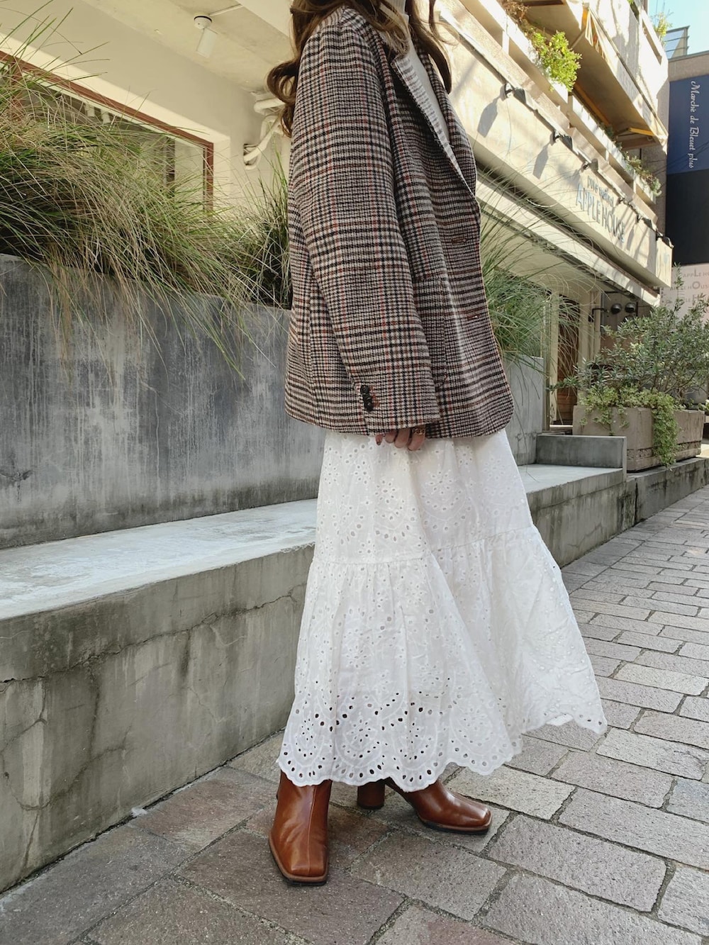 オレンジ系のテーラードジャケット、ホワイト系のニット/セーター、ホワイト系のスカートを着用したレディースの秋コーディネートの3枚目の写真