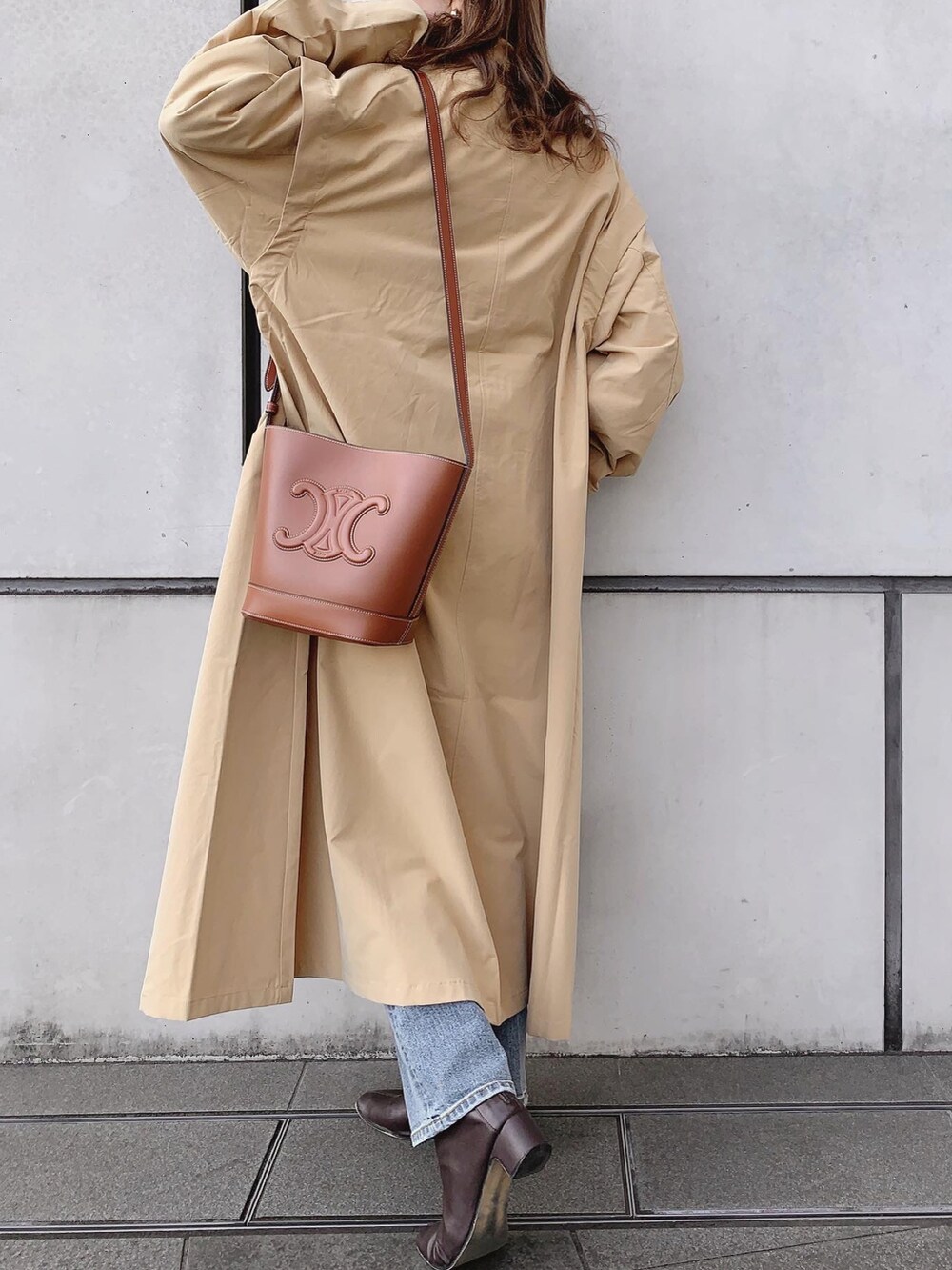 ブルー系のデニムパンツ、ブラウン系のブーツ、ブラック系のニット/セーターを着用したレディースの春コーディネートの4枚目の写真