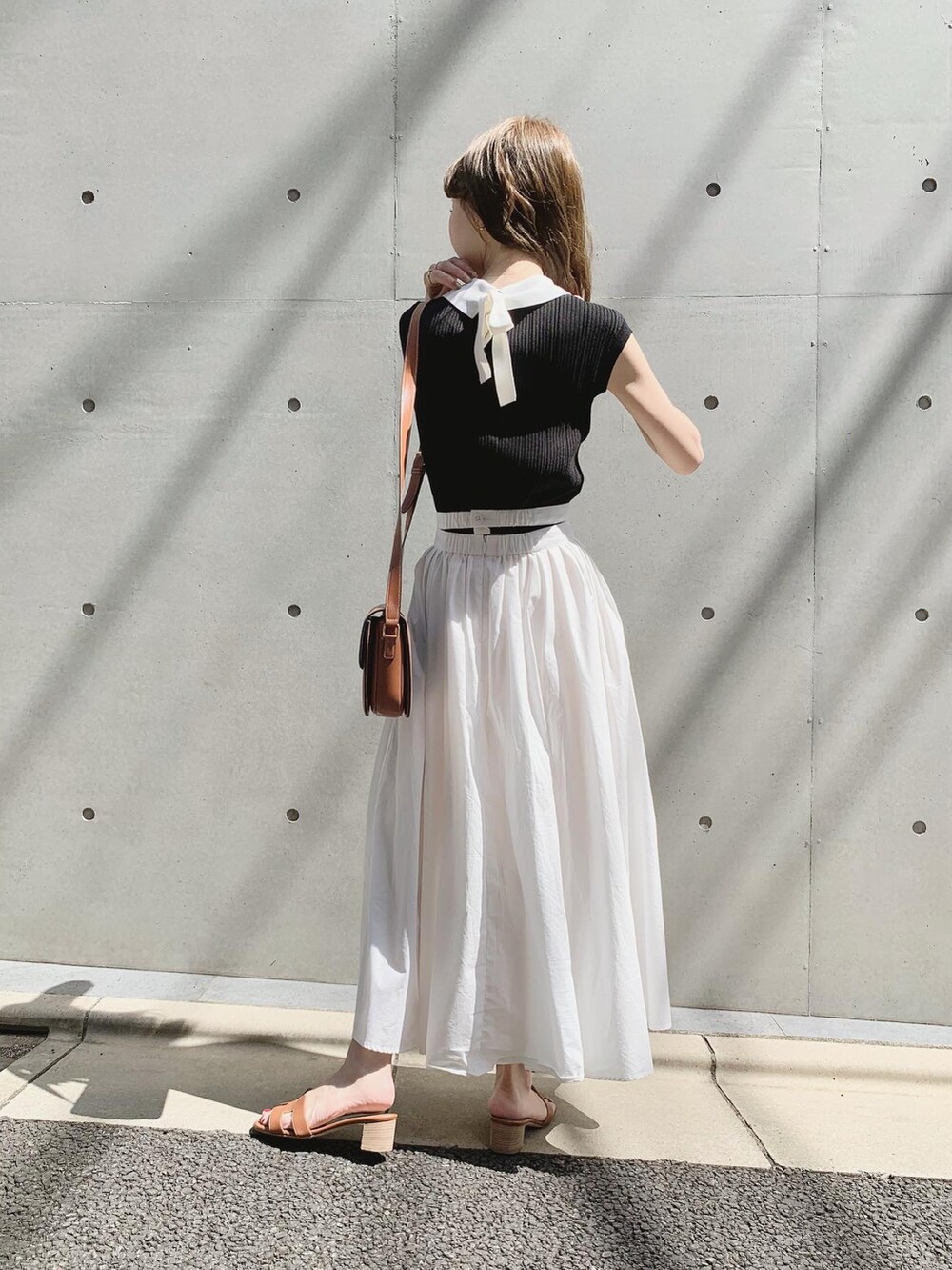 ブラック系のその他トップス、ホワイト系のスカート、ブラウン系のバッグを着用したレディースの夏コーディネートの3枚目の写真