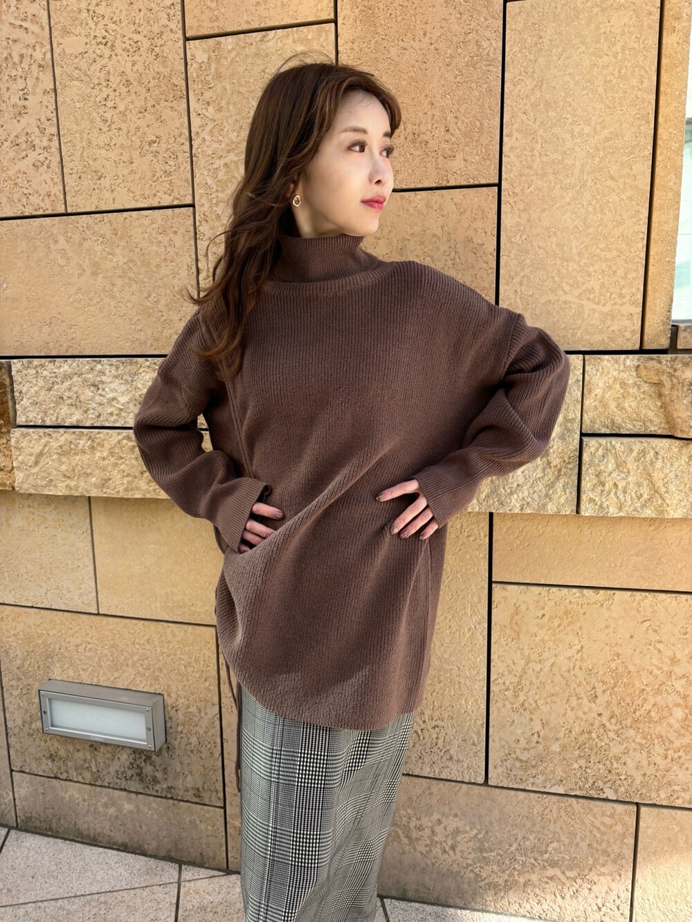 ブラウン系のニット/セーター、ブラック系のスカート、ブラウン系のブーツを着用したレディースの冬コーディネートの2枚目の写真