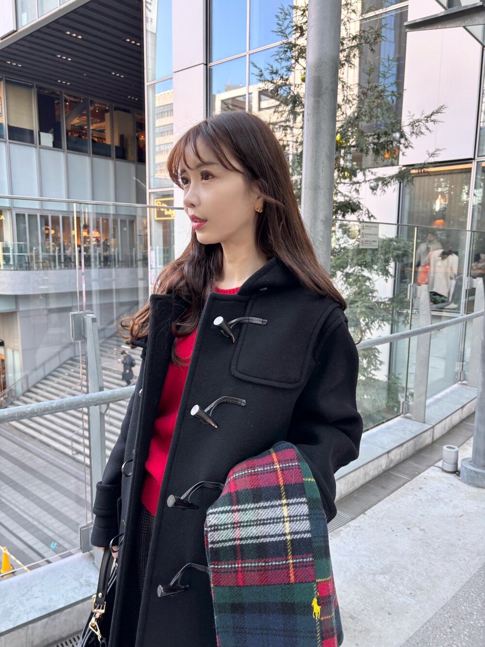 ブラック系のダッフルコート、レッド系のニット/セーター、ブラウン系のその他パンツを着用したレディースの冬コーディネートの2枚目の写真