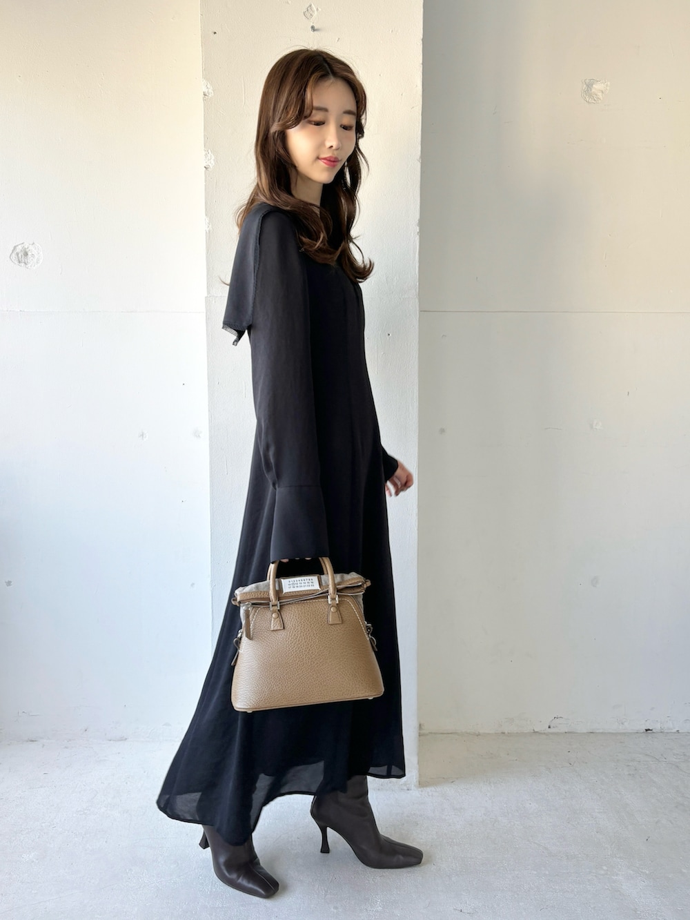 ブラック系のワンピース、ブラウン系のブーツを着用したレディースの冬コーディネートの2枚目の写真