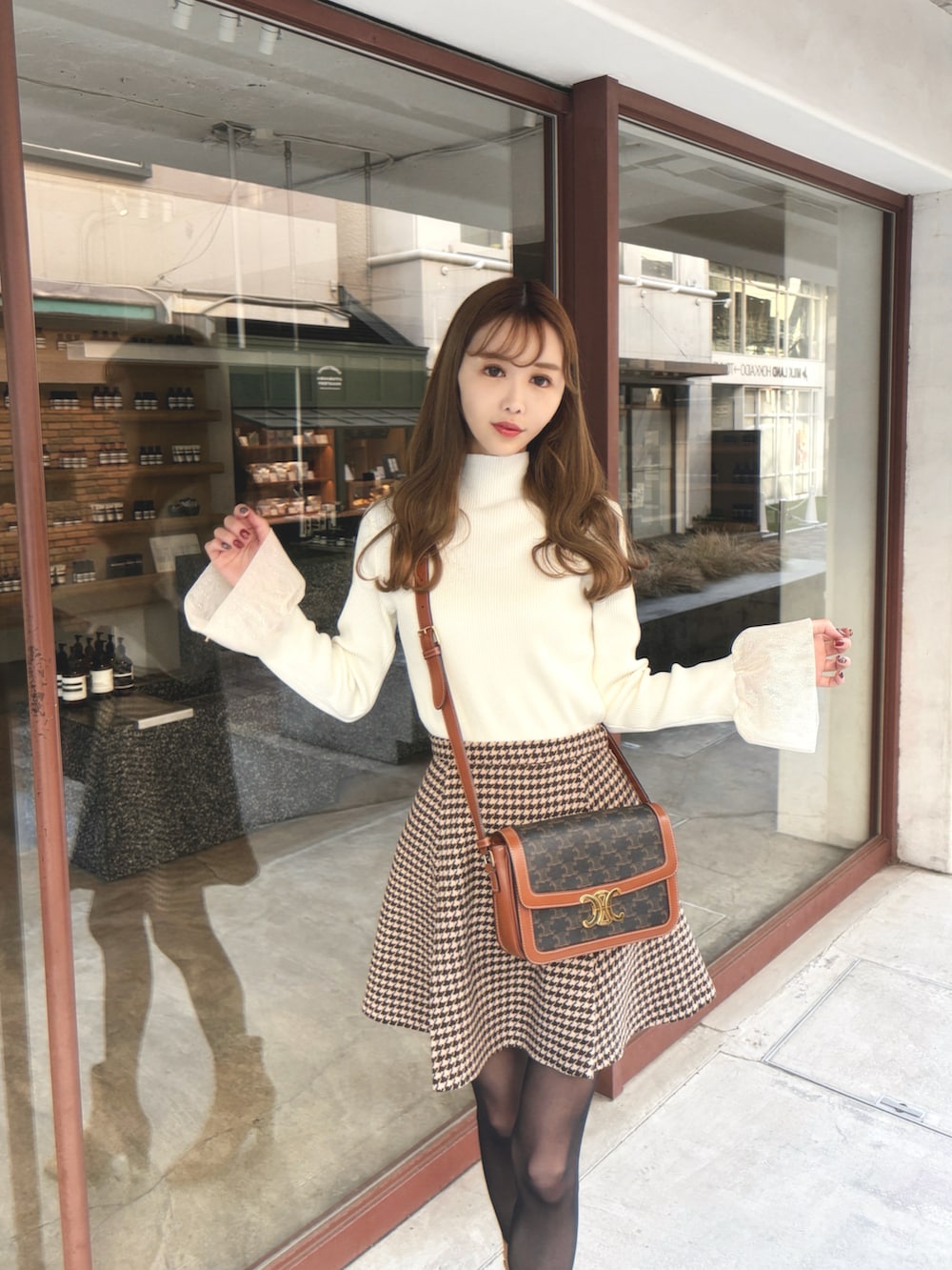 ホワイト系のニット/セーター、ブラウン系のスカートを着用したレディースの冬コーディネートの2枚目の写真