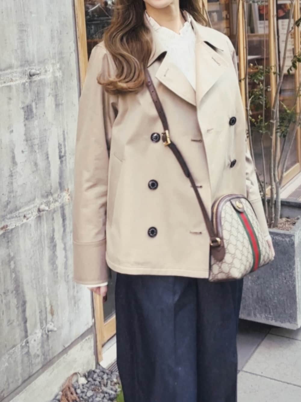 ベージュ系のトレンチコート、ホワイト系のシャツ/ブラウス、ブルー系のその他パンツを着用したレディースの春コーディネートの3枚目の写真