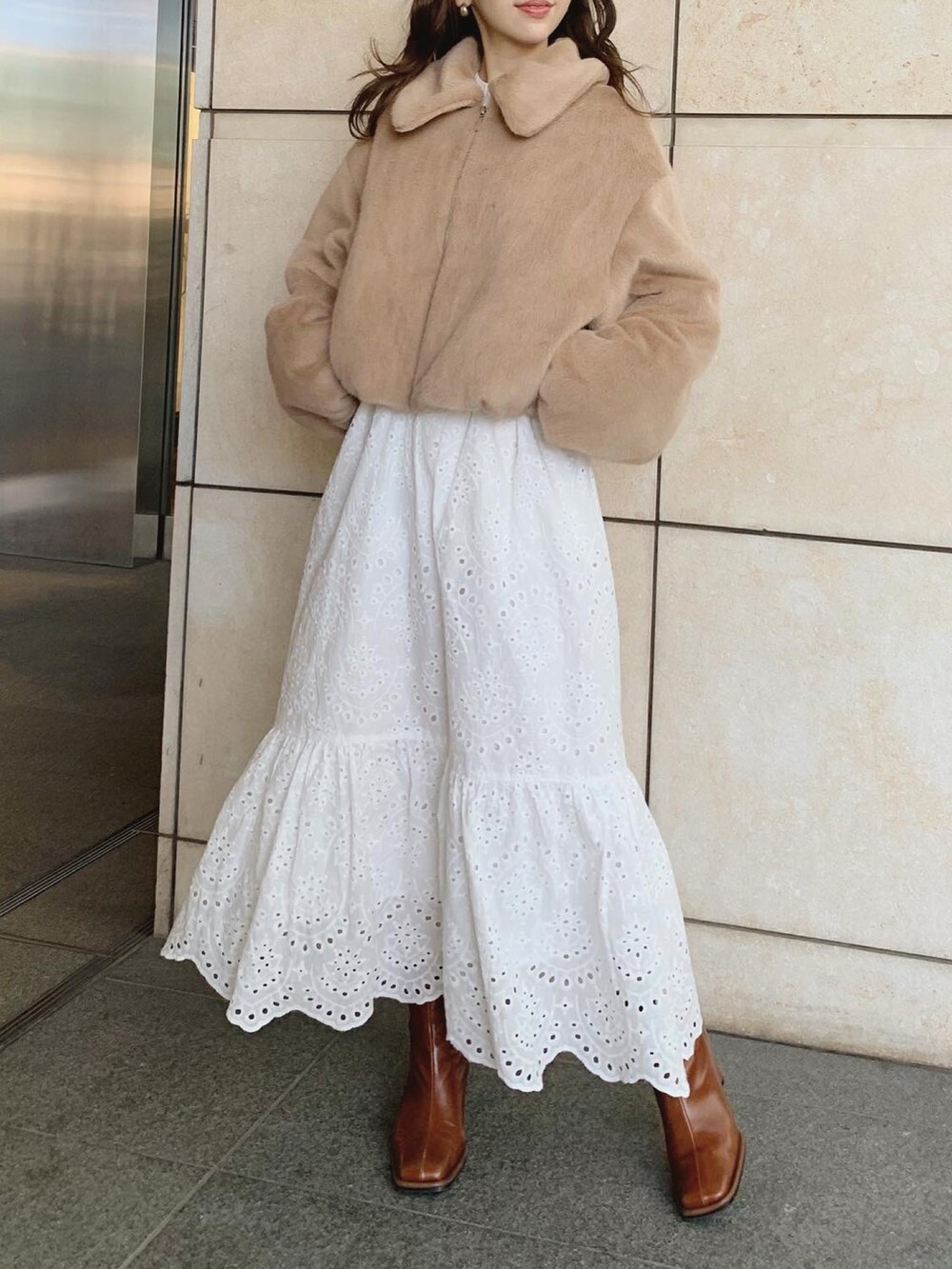 ホワイト系のスカート、ベージュ系のブルゾン、ブラウン系のブーツを着用したレディースの秋コーディネートの2枚目の写真