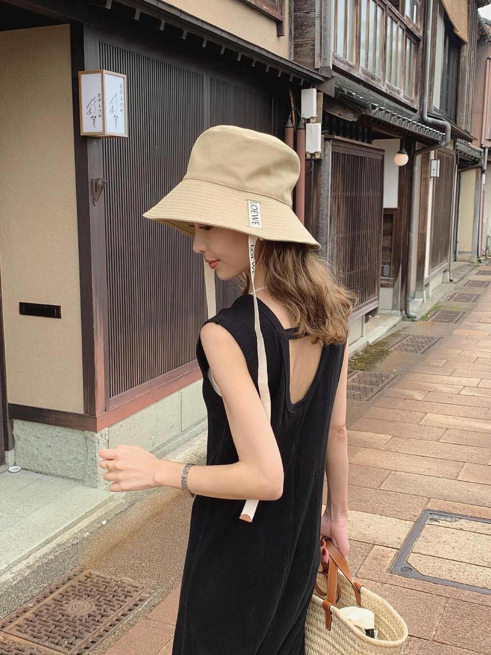 ブラック系のワンピース、ブラウン系のサンダル、ブラウン系のバッグを着用したレディースの夏コーディネートの2枚目の写真